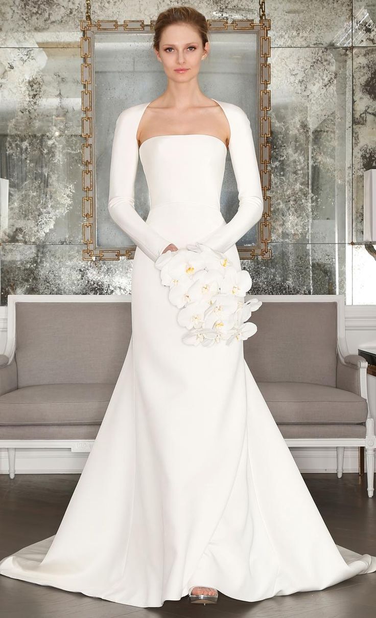 a woman in a white wedding dress standing next to a couch with flowers on it