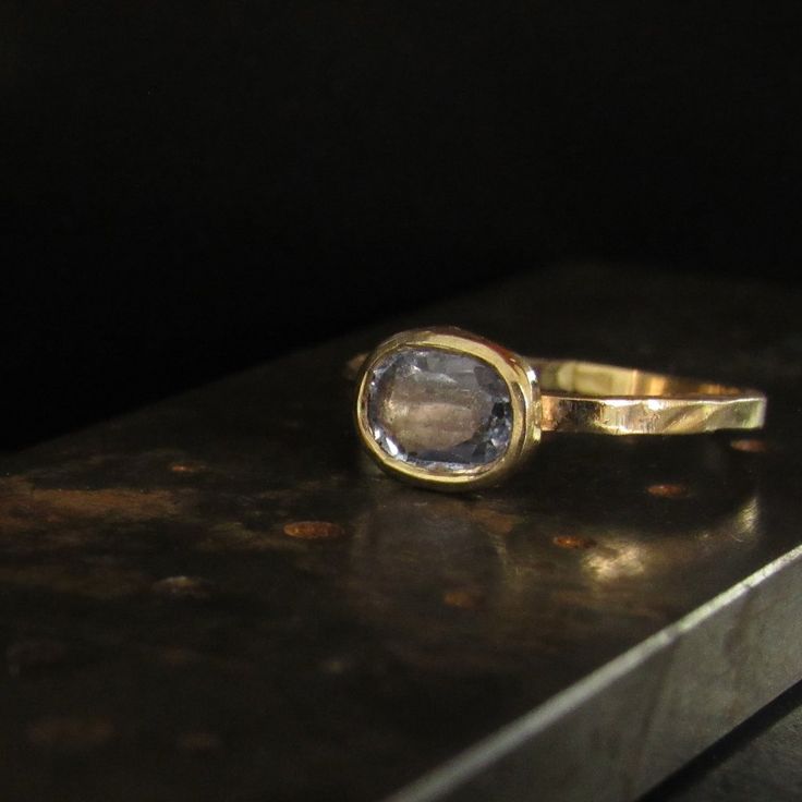 a close up of a gold ring with a stone in the middle on a table