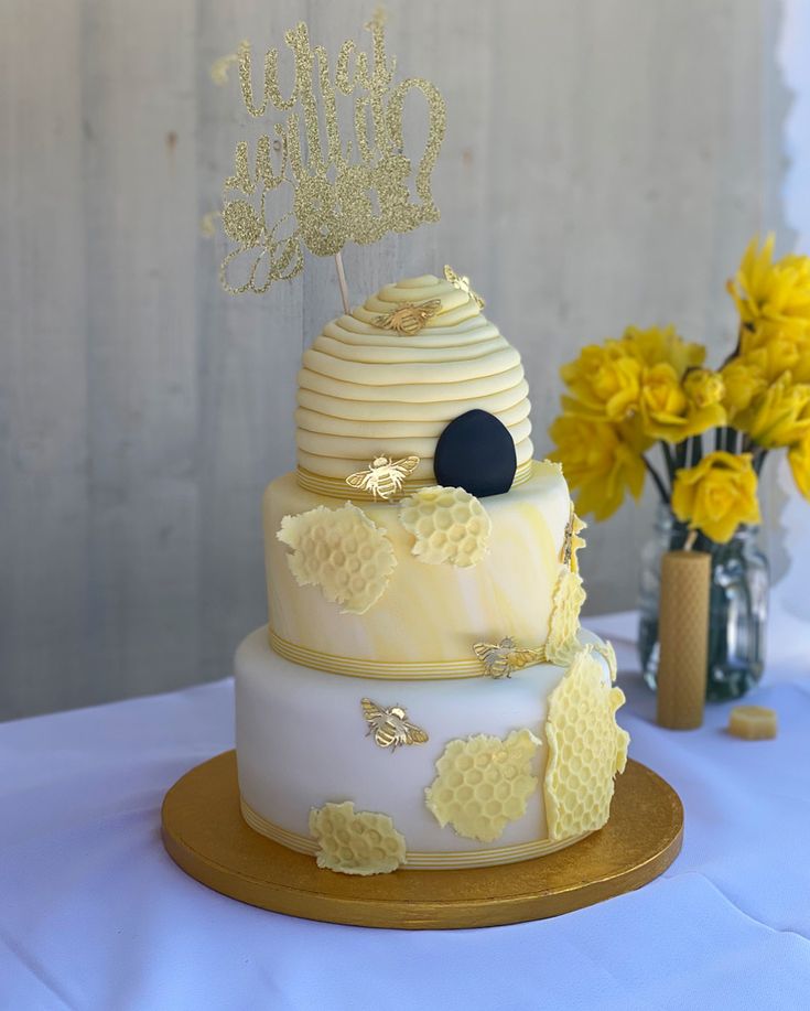 a three tiered cake decorated with honeycombs and beehive on top