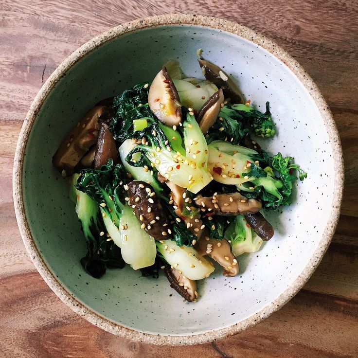 a bowl filled with broccoli, mushrooms and sesame seeds