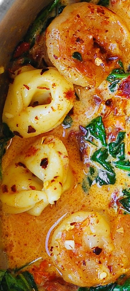 a pot filled with pasta and spinach covered in sauce