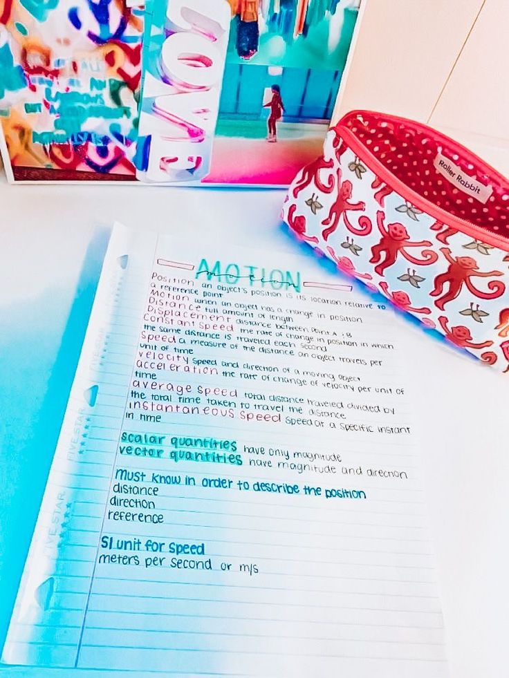 an open notebook sitting on top of a table next to a pencil bag and magazine