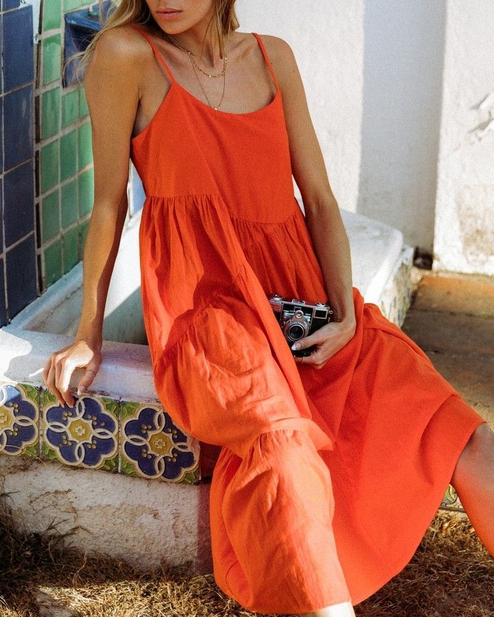 On vacation in an orange tiered midi tank dress with a vintage camera Sleeveless Cotton Tiered Dress For Brunch, Cotton Tiered Dress For Beach, Tiered Dress For Summer, Chic Summer Cotton Tiered Dress, Chic Cotton Tiered Summer Dress, Summer Linen Maxi Dress With Ruffles, Beach Tiered Cotton Dress, Cotton Tiered Summer Beach Dress, Beach Tiered Cotton Dress With Ruffle Hem