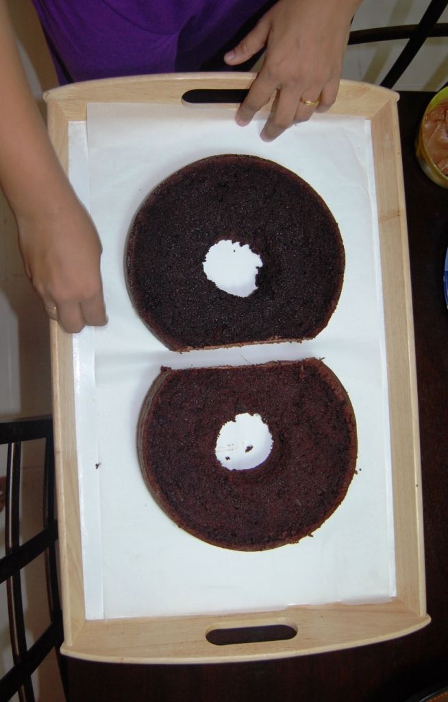 two chocolate donuts with white frosting are in a cardboard box on a table