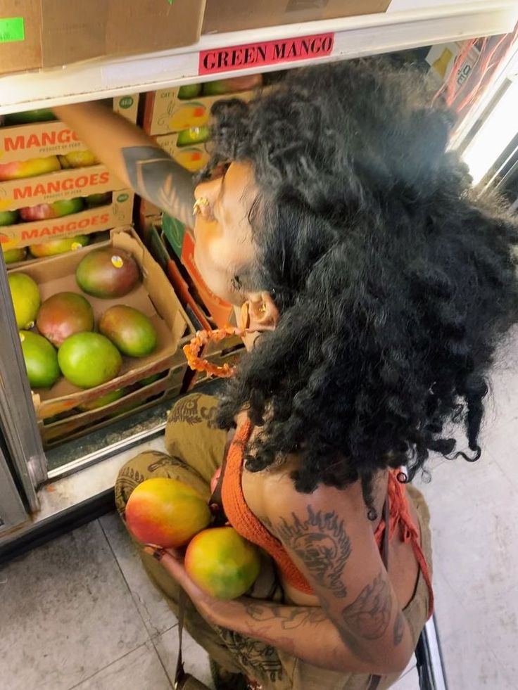 a woman standing in front of a refrigerator filled with fruit