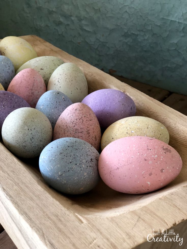 several different colored eggs in a wooden bowl