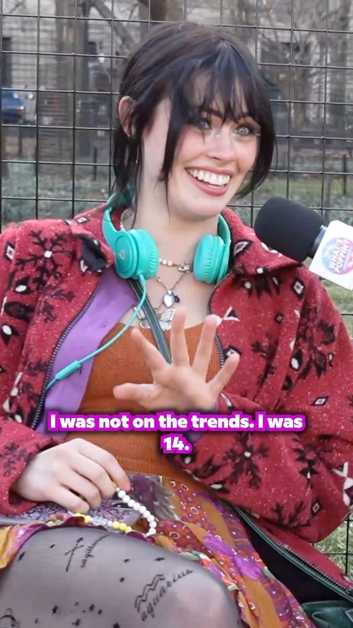 a woman with headphones on sitting in front of a microphone and holding her hand up