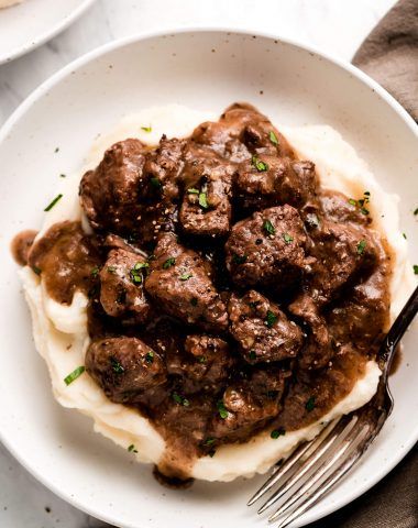 meatballs and mashed potatoes on a white plate with a fork in the foreground