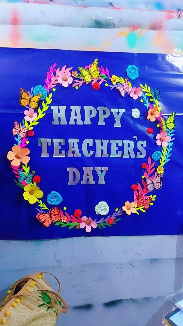 a blue sign that says happy teachers day with flowers and leaves around the letters on it