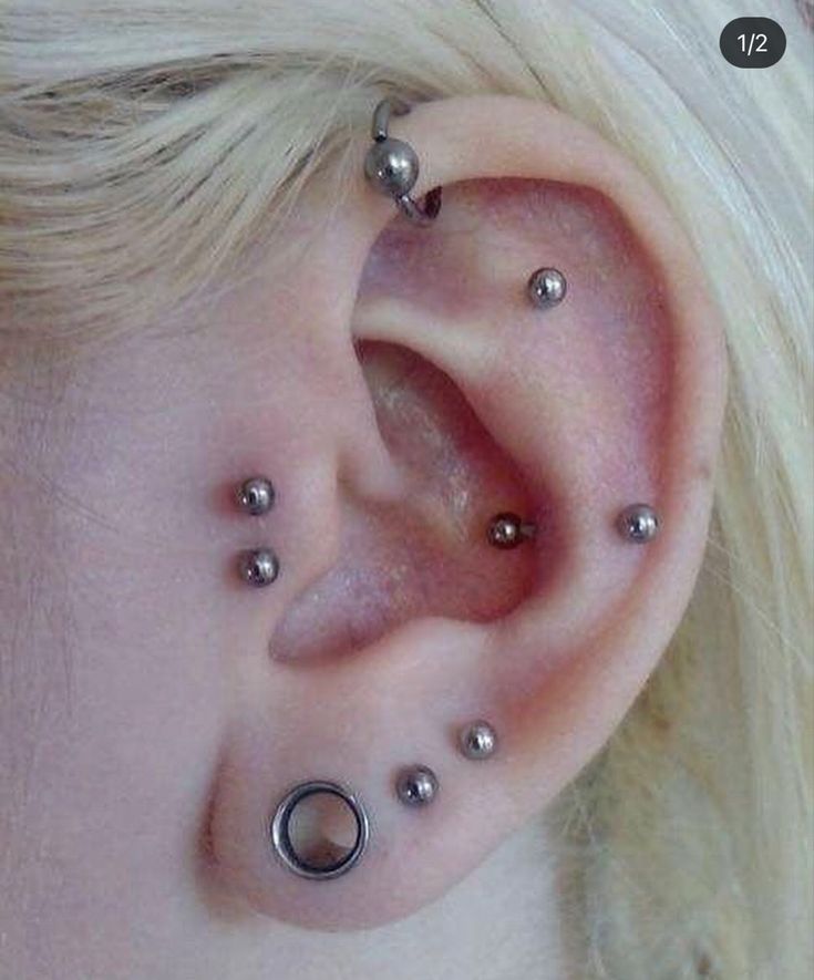 a close up of a person with piercings on their ears and behind the ear