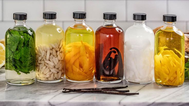 six bottles filled with different types of liquid and ingredients next to each other on a counter