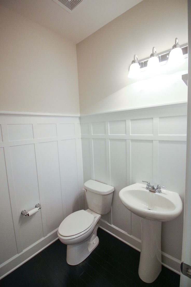 a white toilet sitting next to a sink in a bathroom on top of a hard wood floor