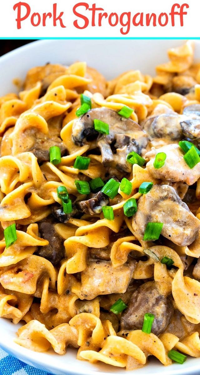 a white bowl filled with pasta covered in mushrooms and green onions, on top of a blue table cloth