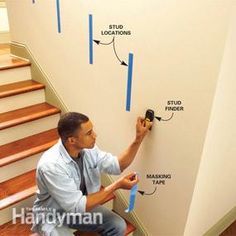 a man is sitting on the stairs with tape around his feet and measuring the wall