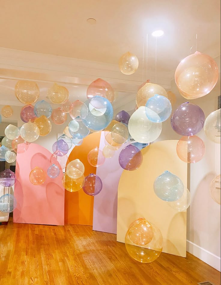 balloons are floating in the air over a wood floored room with white walls and wooden floors