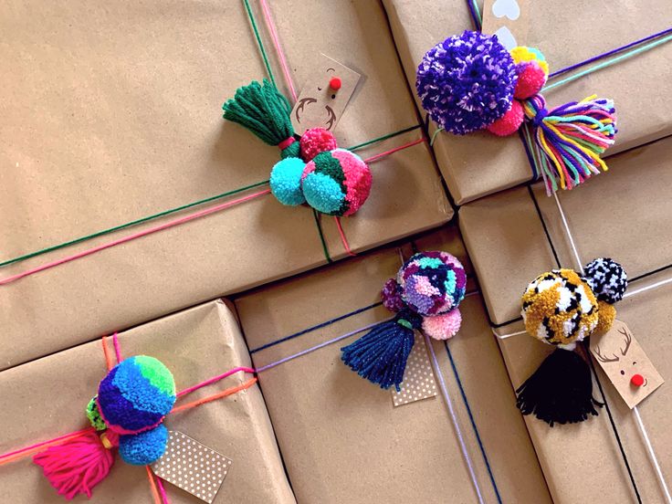 four different colored pom poms tied together on brown wrapping paper with tags attached to them