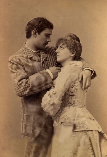 an old fashion photo of a man adjusting the collar of a woman's dress