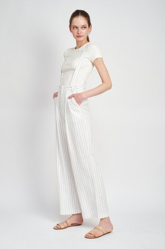 This Hits Different Jumpsuit combines fashion and function. With high waist pinstripe trousers and detachable suspenders, you get a sleek and sophisticated look with the flexibility to style it up or down. Perfect for any occasion. Size Chart Small Medium Large Bust 34 36 38 Waist 26 28 30 High Hip 34 36 38 Low Hip 37 39 41 **in inches** MODEL WEARS SIZE SMALLMODEL'S HEIGHT 5'9 Fabric Contents: 70% RAYON, 30% LINEN Chic Spring Bottoms With Suspenders, Chic Workwear Jumpsuits And Rompers With Suspenders, Chic Jumpsuits And Rompers With Suspenders For Work, Chic Jumpsuit With Suspenders For Work, Chic High Waist Bottoms With Suspenders, Chic Fitted Bottoms With Vertical Stripes, Elegant High Waist Pinstripe Pants, Elegant High-waist Pinstripe Pants, Chic Fitted Bottoms With Suspenders