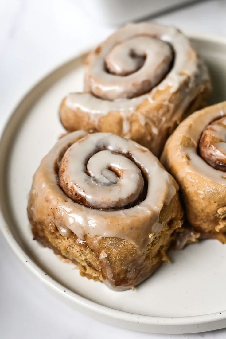 three glazed cinnamon rolls on a plate