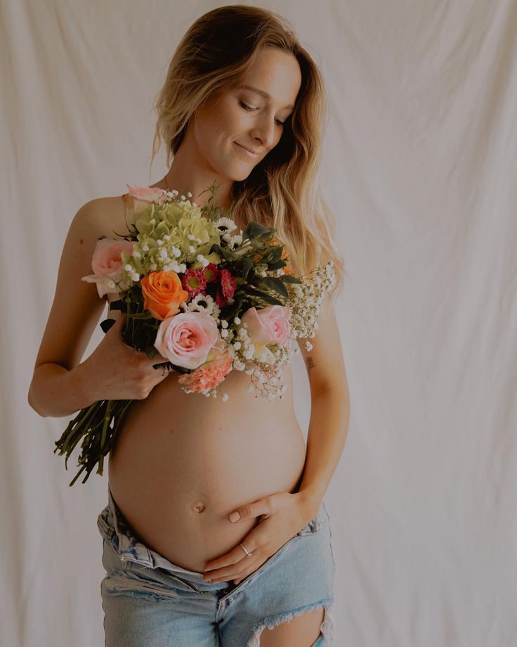 a pregnant woman holding flowers in her belly