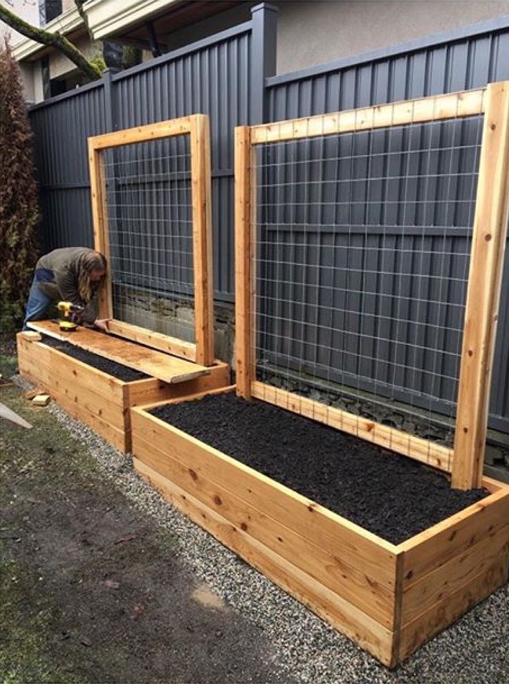 an outdoor garden area with raised beds and plants in the center, surrounded by gravel