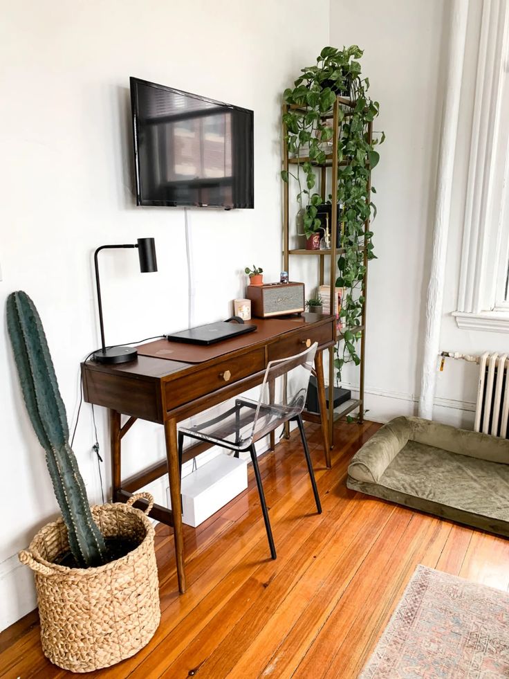 a living room with a desk, chair and television