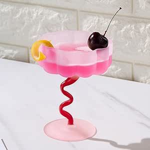 a pink drink with a cherry on the rim and a yellow slice in it sitting on a white table