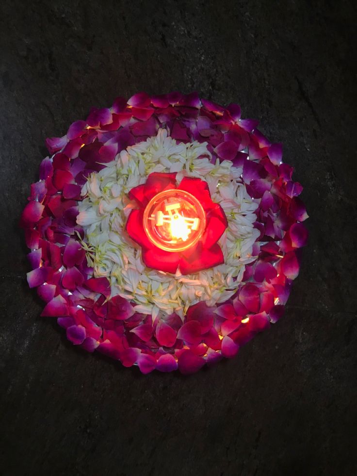 a lit candle is surrounded by flowers and petals