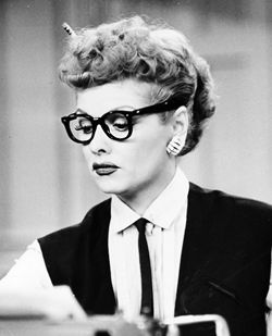 a woman wearing glasses sitting at a desk