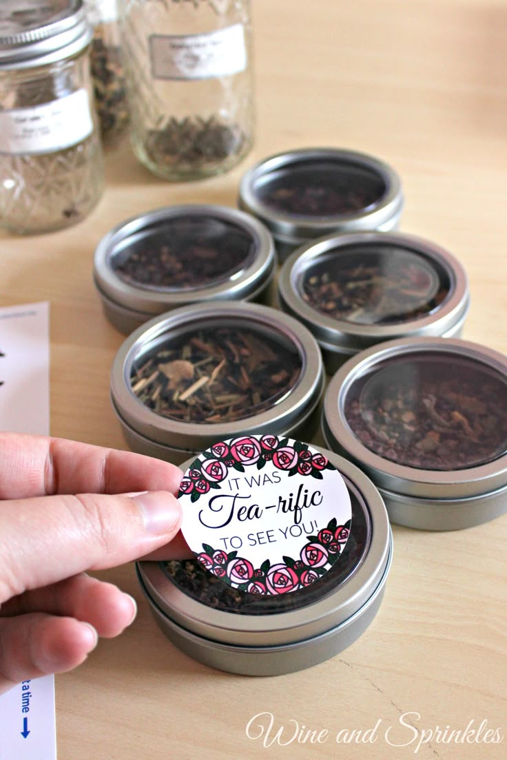 a person is holding up a sticker that says tea in the middle of six jars