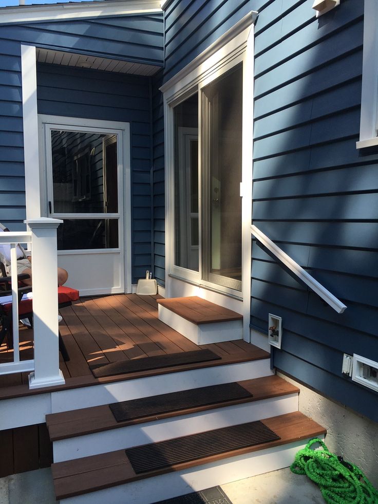 a house with blue siding and wooden steps leading up to the front door that is open