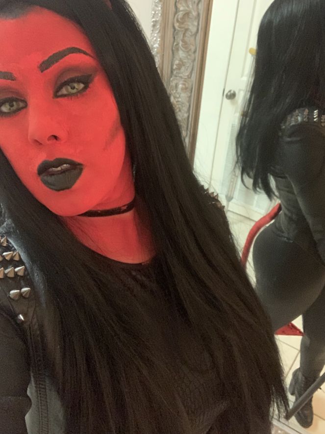 a woman with long black hair and red makeup is taking a selfie in front of a mirror