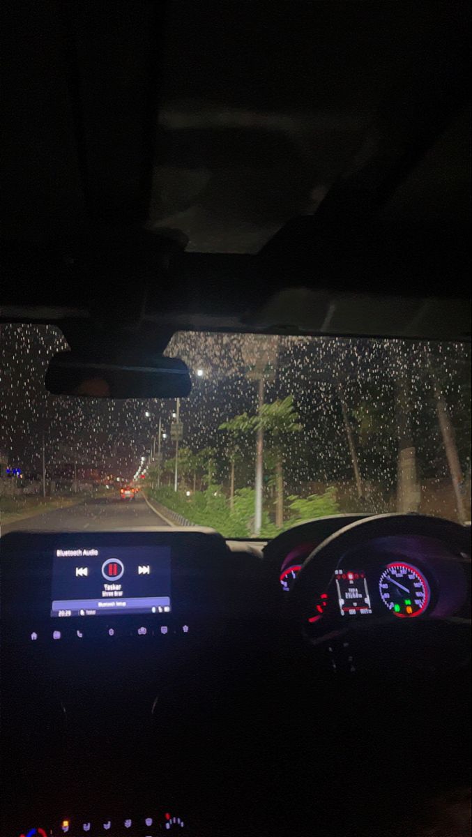 the dashboard of a car at night with rain falling down on it's windshield