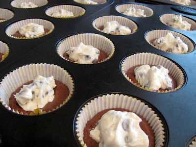 cupcakes with white frosting sitting on top of each other in muffin tins