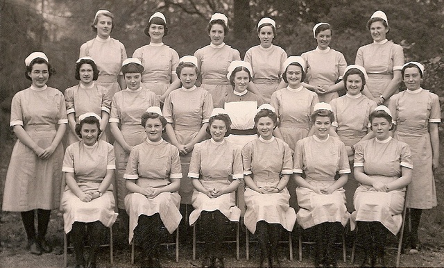 an old black and white photo of women in tennis uniforms posing for a group photograph