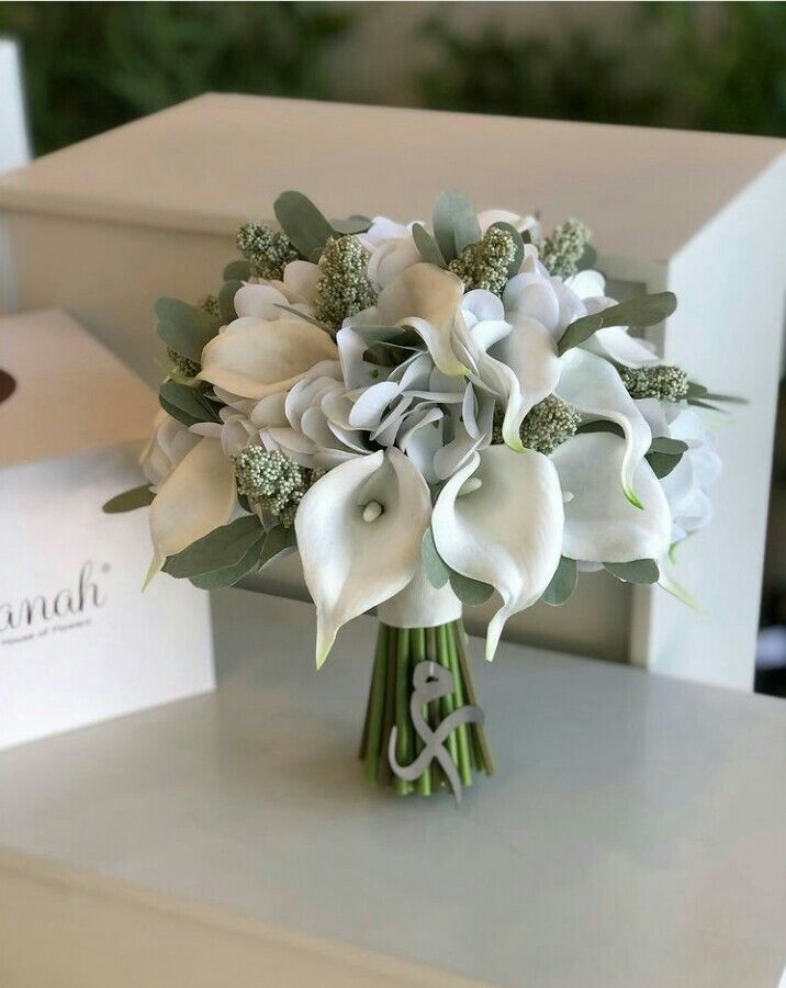 a bouquet of white flowers sitting on top of a table next to a card box