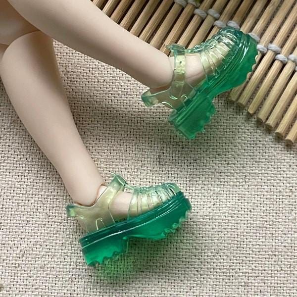 a close up of a doll's legs wearing green shoes and heels on the floor