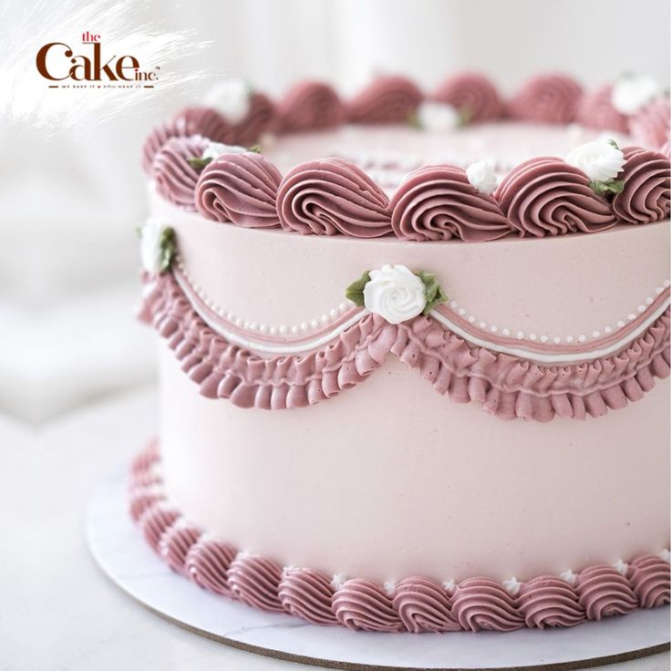 a close up of a cake with pink icing and white flowers on the top