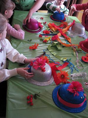 children are sitting at a table with hats on it