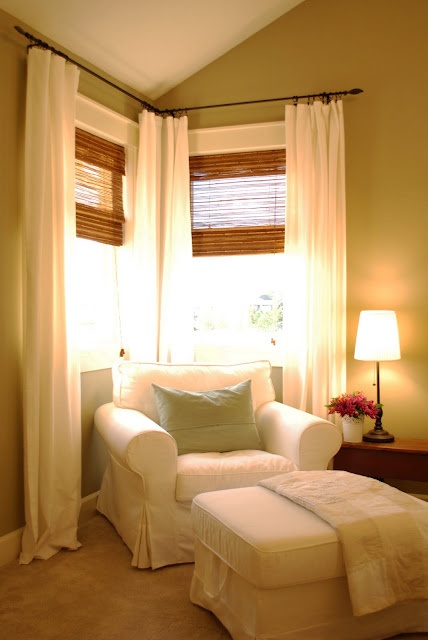 a living room filled with furniture and windows covered in white curtained drapes