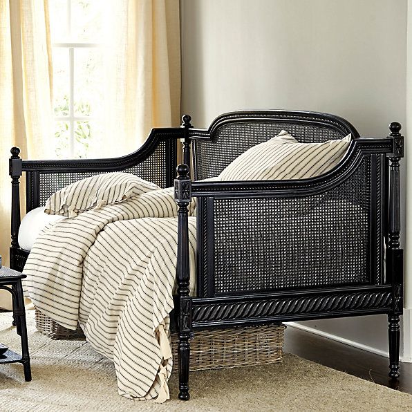 a bedroom with a black bed frame and striped comforter on top of the bed