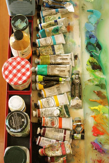 an artist's palette with paints and other items in it on a table top