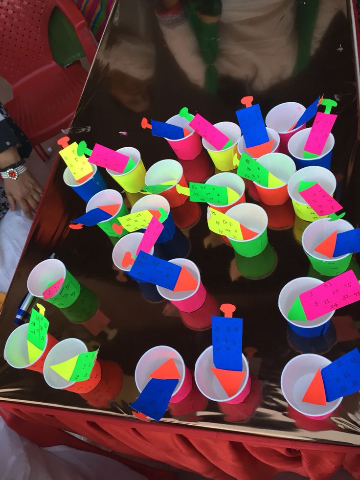 plastic cups filled with different colored shapes and sizes on a metal tray in front of a child's table