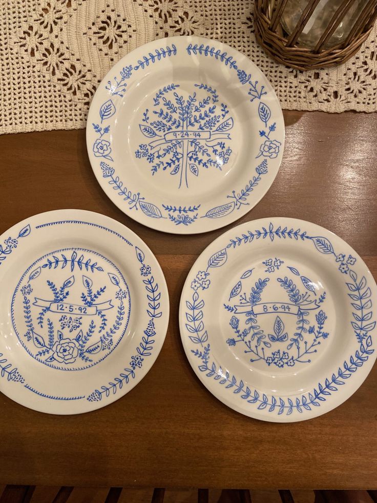 three blue and white plates sitting on top of a wooden table