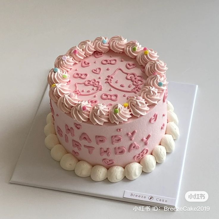 a pink birthday cake with hello kitty decorations on it's icing and frosting