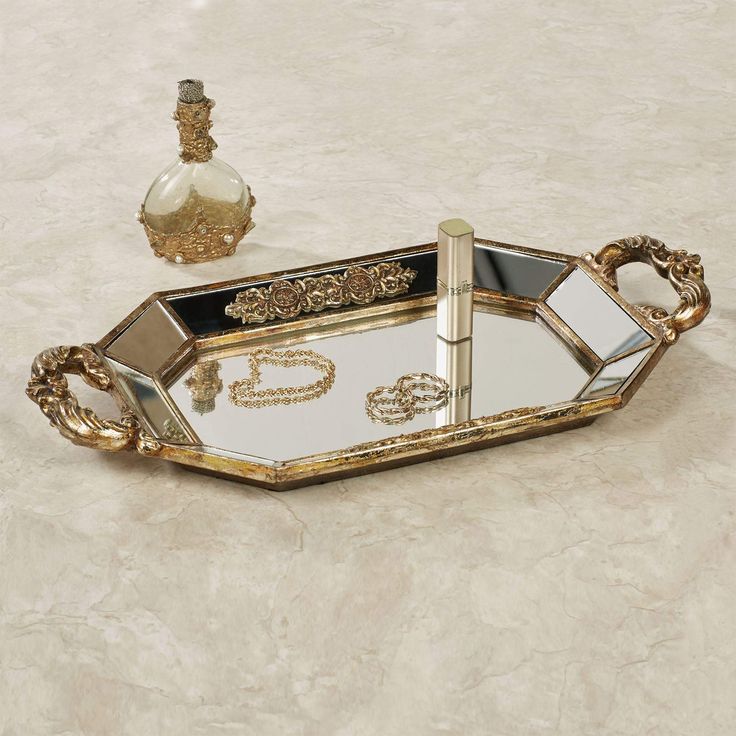 PRICES MAY VARY. This item is our exclusive! Unique mirrored vanity tray Venetian gold finish Scrollwork medallions The Brya Mirrored Vanity Tray exudes a grand grace with classical elements. Finished in marvelous Venetian gold, the resin tray features a faceted shape, a mirrored glass surface, scrollwork medallions, and acanthus leaf handles. Measures 17.5 Wx9 Dx2 H. This item is our exclusive! Unique mirrored vanity tray Venetian gold finish Scrollwork medallions Acanthus leaf handles. Bed Tray Decor, Perfume Stand, Dresser Accessories, Mirrored Vanity, Toilet Paper Stand, Mirror Vanity Tray, Makeup Tray, Elegant Vanity, Gold Tray