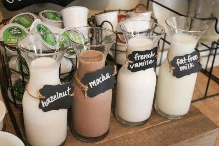 several different types of milk in glass containers on a counter with chalkboard signs attached to them