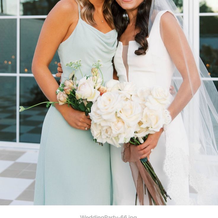 two beautiful women standing next to each other holding bouquets