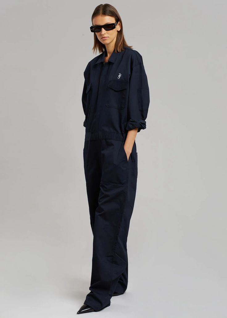 Color: Navy Unisex style Midweight twill fabric Oversized cargo jumpsuit Straight leg Pointed collar  The Frankie Shop logo embroidered on the front and back Elastic tabs at side waist Front flap chest pockets Slant hip pockets Zip and velcro front closure Unlined 65% Polyester 35% Cotton Dry Clean  By The Frankie Shop Cotton Overalls With Multiple Pockets For Work, Utility Jumpsuits And Rompers For Workwear, Utility Overalls With Pockets For Workwear, Solid Denim Jumpsuit With Pockets For Work, Cotton Jumpsuits With Cargo Pockets For Fall, Fall Cotton Jumpsuits With Cargo Pockets, Cotton Jumpsuits And Rompers With Cargo Pockets For Fall, Fall Cotton Jumpsuits And Rompers With Cargo Pockets, Cotton Overalls With Pockets For Work