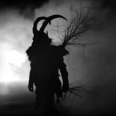 a man with horns and long hair standing in the dark